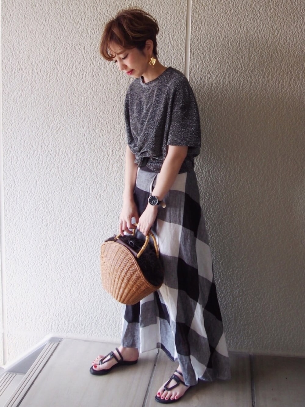 ブラック系のトップス、その他のスカート、ベージュ系のかごバッグを着用したレディースの春コーディネートの1枚目の写真