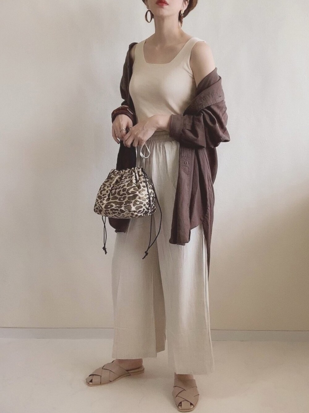 ベージュ系のその他パンツ、その他のハンドバッグ、ブラック系のシャツ/ブラウスを着用したレディースの夏コーディネートの1枚目の写真