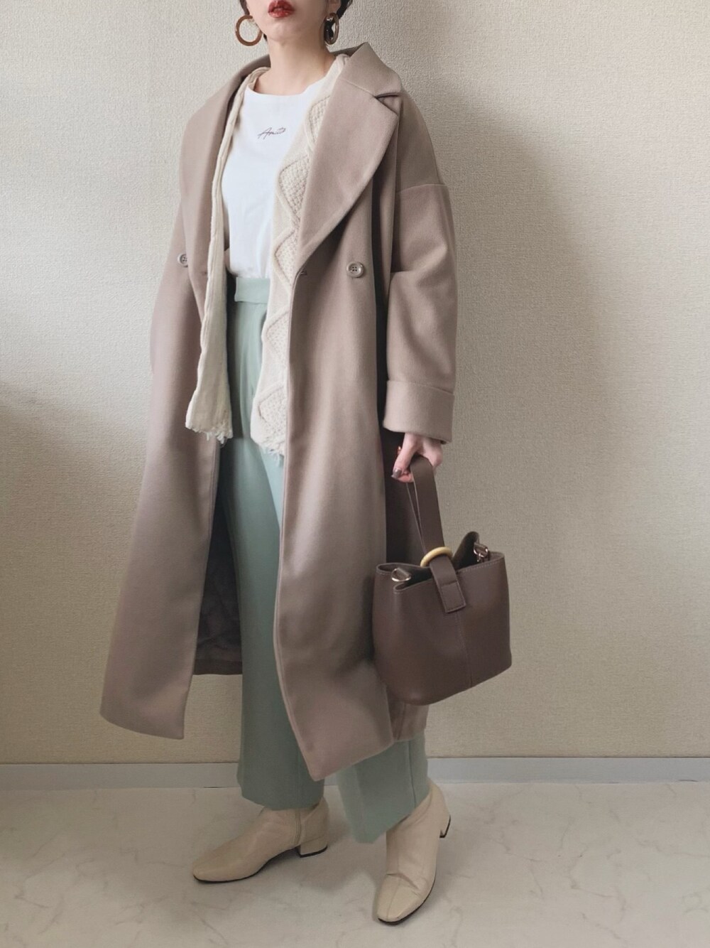 ベージュ系のチェスターコート、ホワイト系のカーディガン/ボレロ、グリーン系のその他パンツを着用したレディースの冬コーディネートの1枚目の写真
