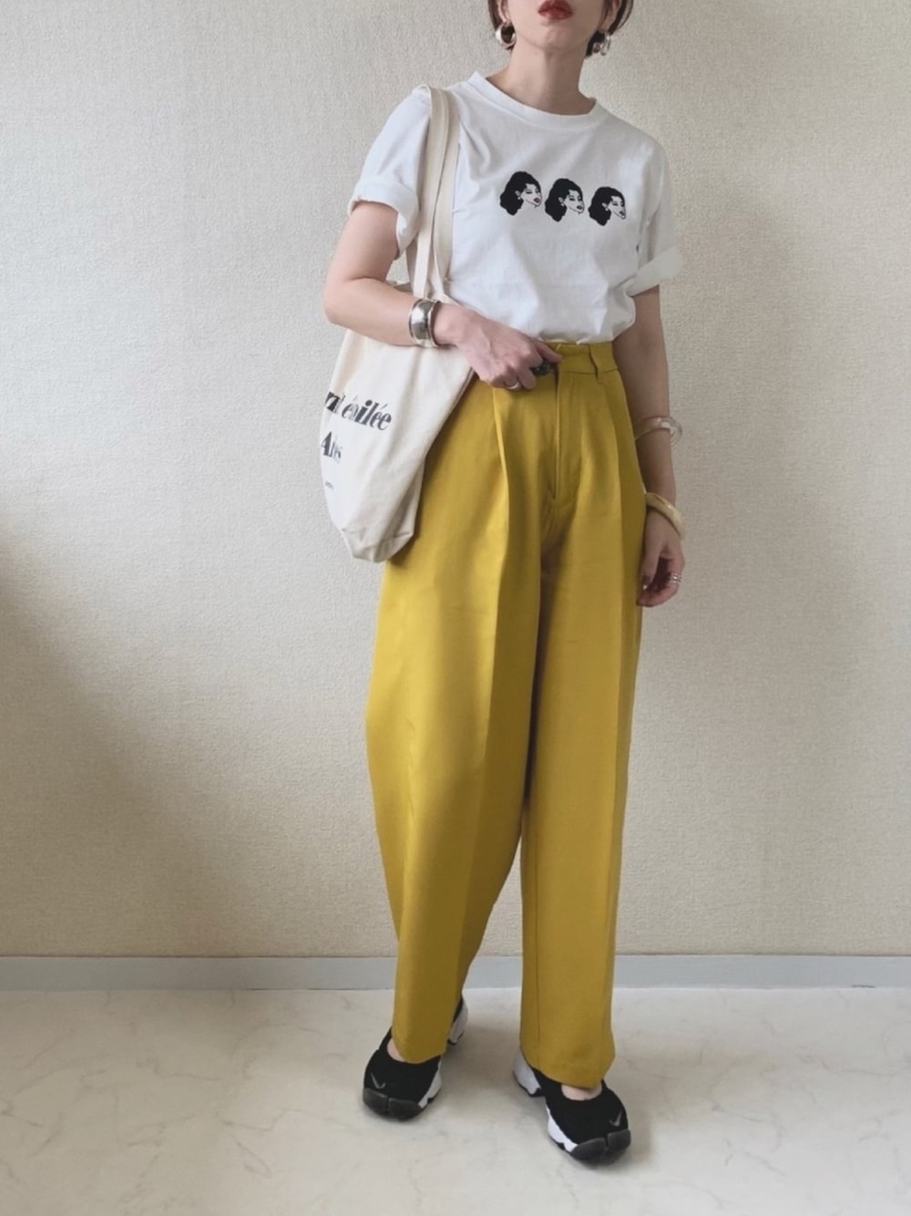 ホワイト系のTシャツ/カットソー、イエロー系のスラックス、ブラック系のスニーカーを着用したレディースの夏コーディネートの1枚目の写真