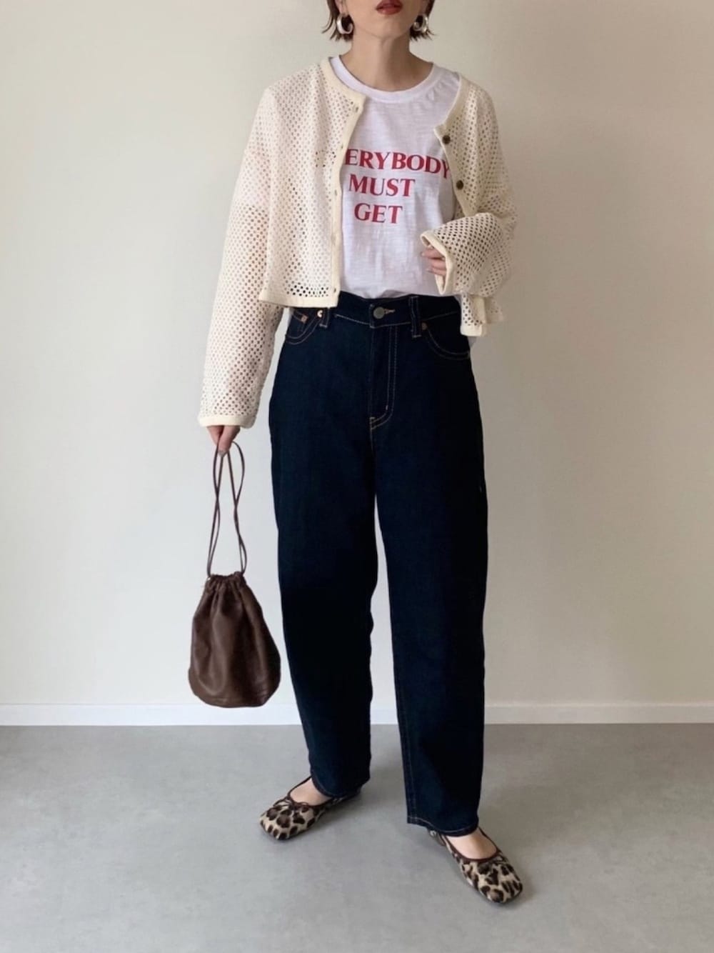 ホワイト系のTシャツ/カットソー、ブルー系のデニムパンツ、ベージュ系のカーディガン/ボレロを着用したレディースの秋コーディネートの1枚目の写真