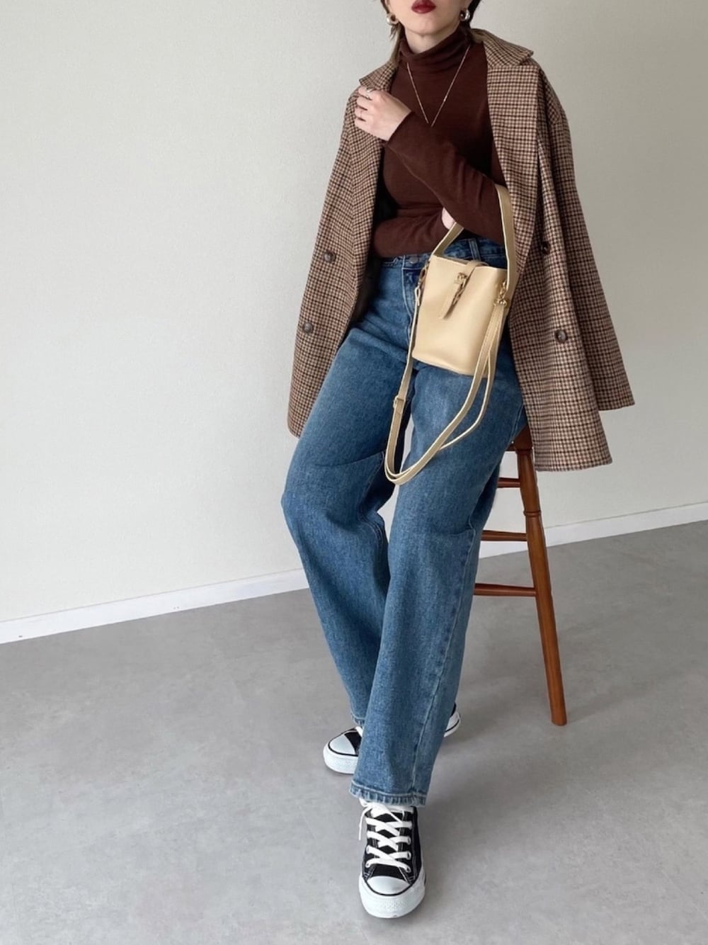 ブルー系のデニムパンツ、ベージュ系のドラムバッグ、ベージュ系のテーラードジャケットを着用したレディースの冬コーディネートの1枚目の写真