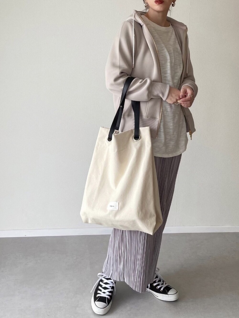 ベージュ系のパーカー、ホワイト系のTシャツ/カットソー、ホワイト系のトートバッグを着用したレディースの冬コーディネートの1枚目の写真