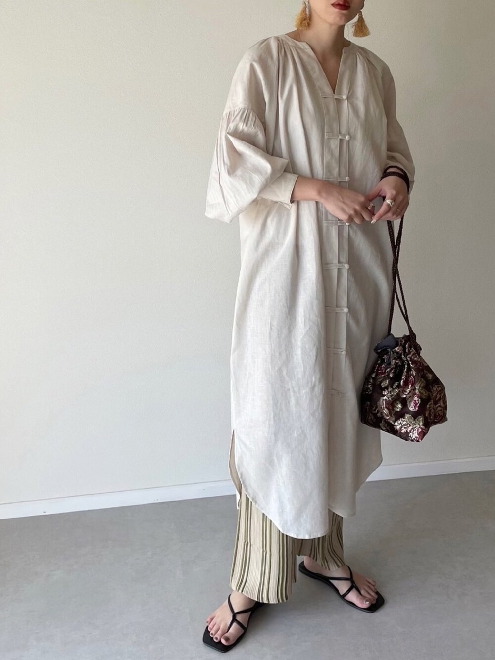 ホワイト系のシャツワンピース、ブラウン系のハンドバッグ、ベージュ系のレギンス/スパッツを着用したレディースの春コーディネートの1枚目の写真