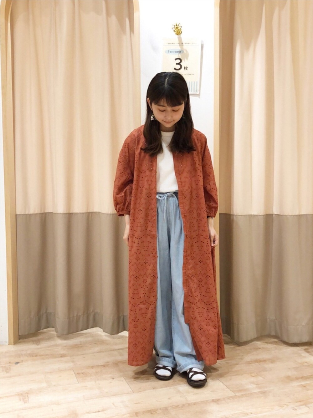 オレンジ系のワンピース、ホワイト系のシャツ/ブラウス、ブルー系のデニムパンツを着用したレディースの春コーディネートの1枚目の写真