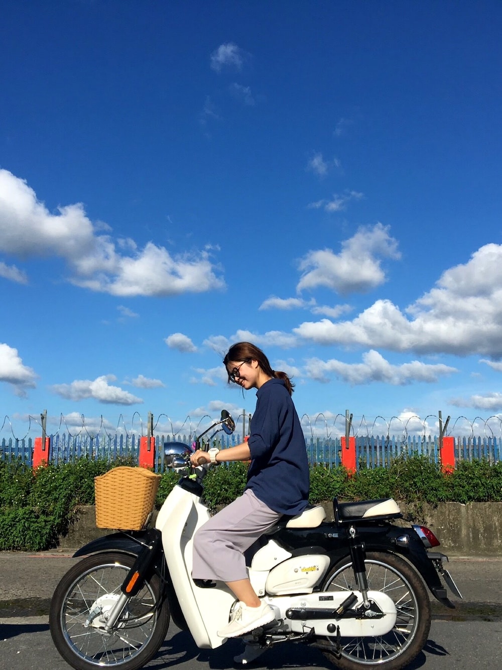 ホワイト系のスニーカー、ブルー系のシャツ/ブラウス、ホワイト系のアナログ腕時計を着用したレディースの夏コーディネートの1枚目の写真