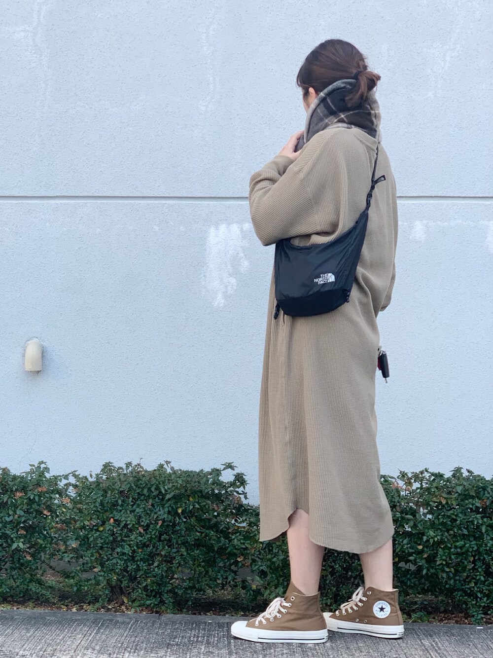 ベージュ系のワンピース、ブラック系のショルダーバッグ、ブラウン系のスニーカーを着用したレディースの春コーディネートの1枚目の写真