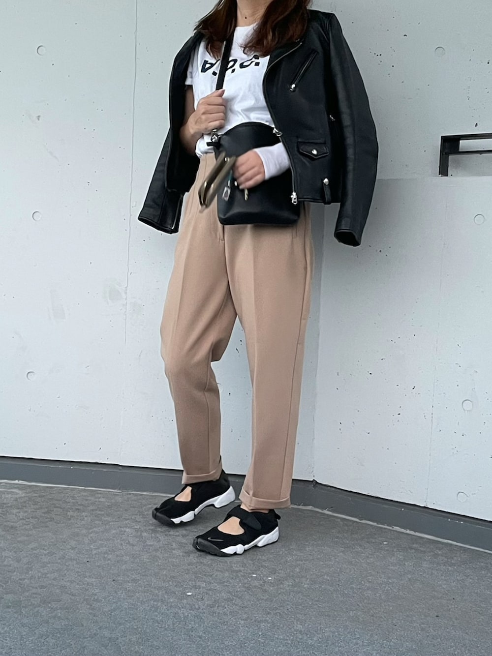 ホワイト系のTシャツ/カットソー、ブラック系のライダースジャケット、ベージュ系のパンツを着用したレディースの秋コーディネートの1枚目の写真