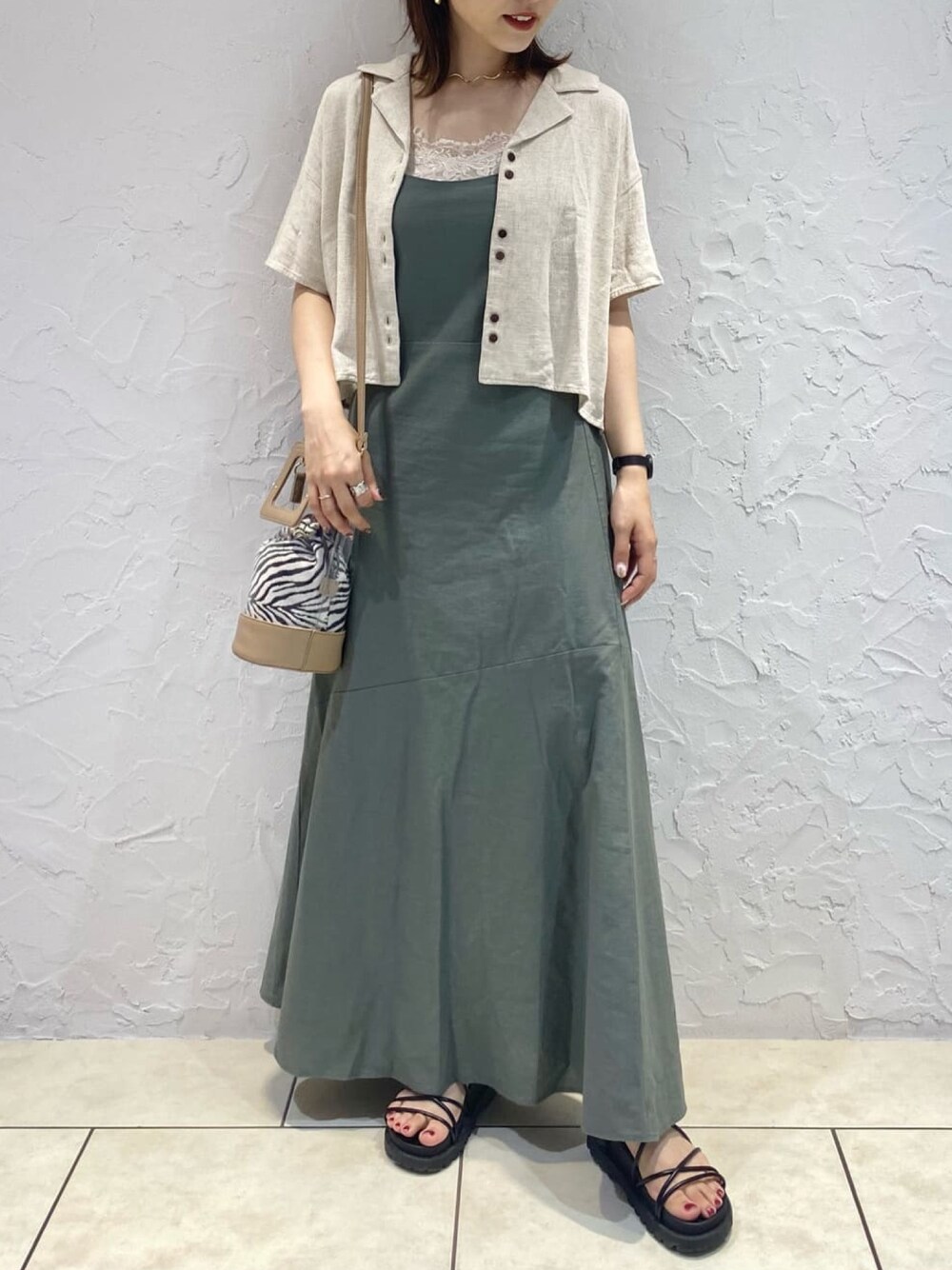 ベージュ系のショルダーバッグ、ホワイト系のシャツ/ブラウス、ブラック系のサンダルを着用したレディースの夏コーディネートの1枚目の写真