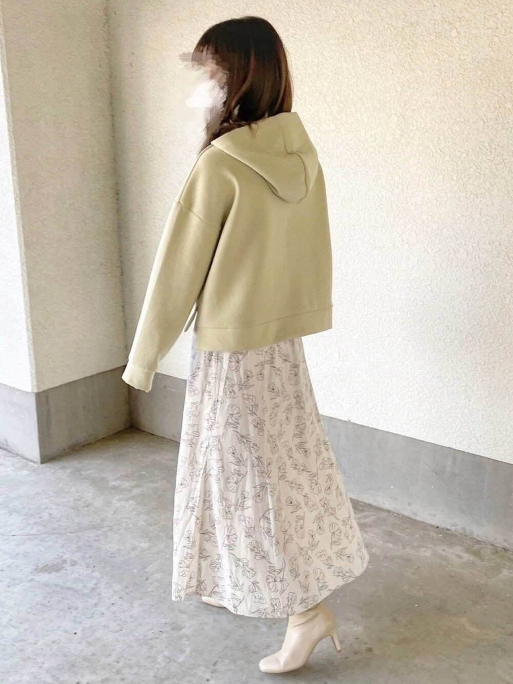 ホワイト系のスカート、ベージュ系のブーツ、グリーン系のパーカーを着用したレディースの春コーディネートの1枚目の写真