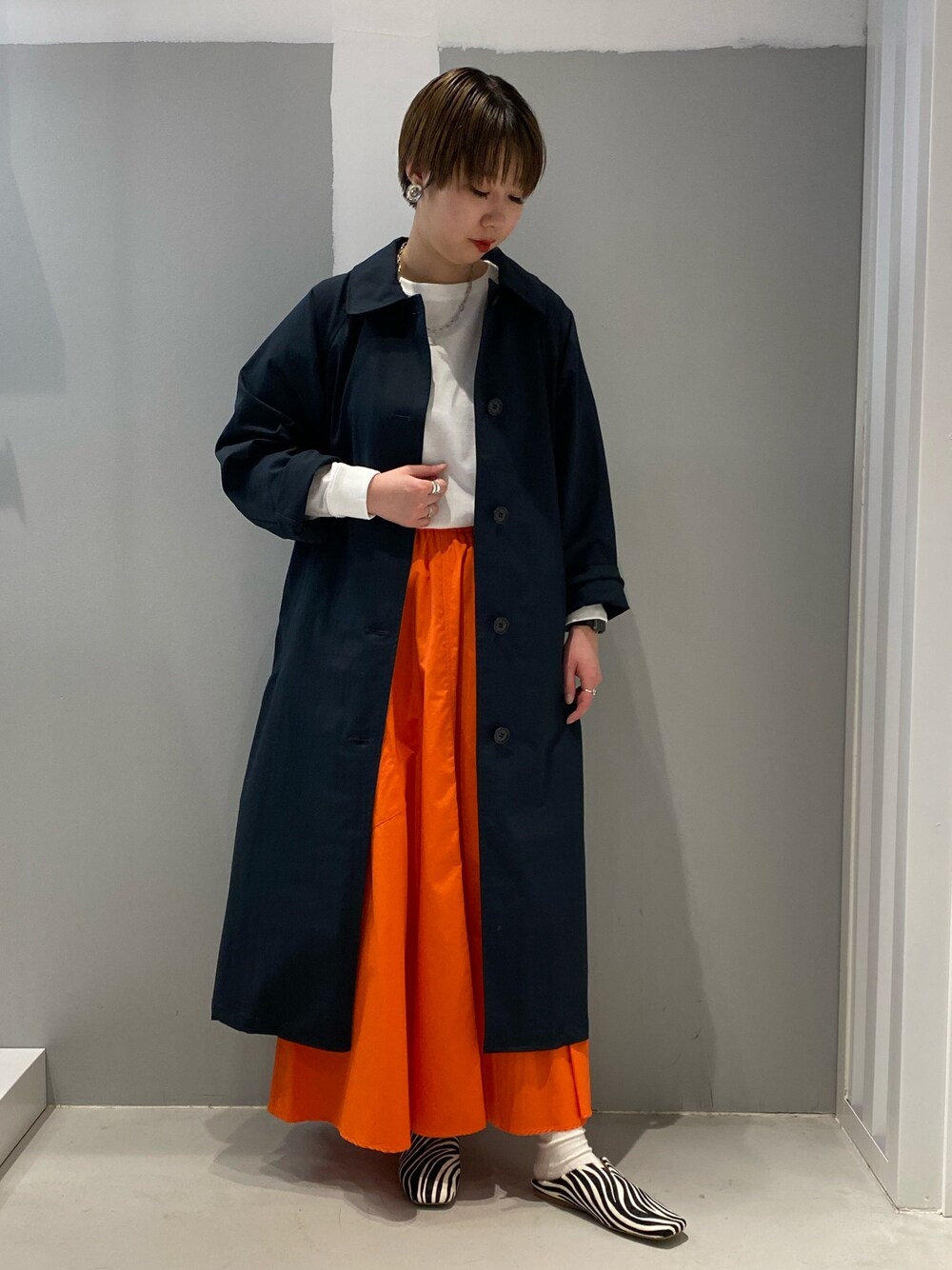 ブルー系のステンカラーコート、ホワイト系のTシャツ/カットソーを着用したレディースの春コーディネートの1枚目の写真