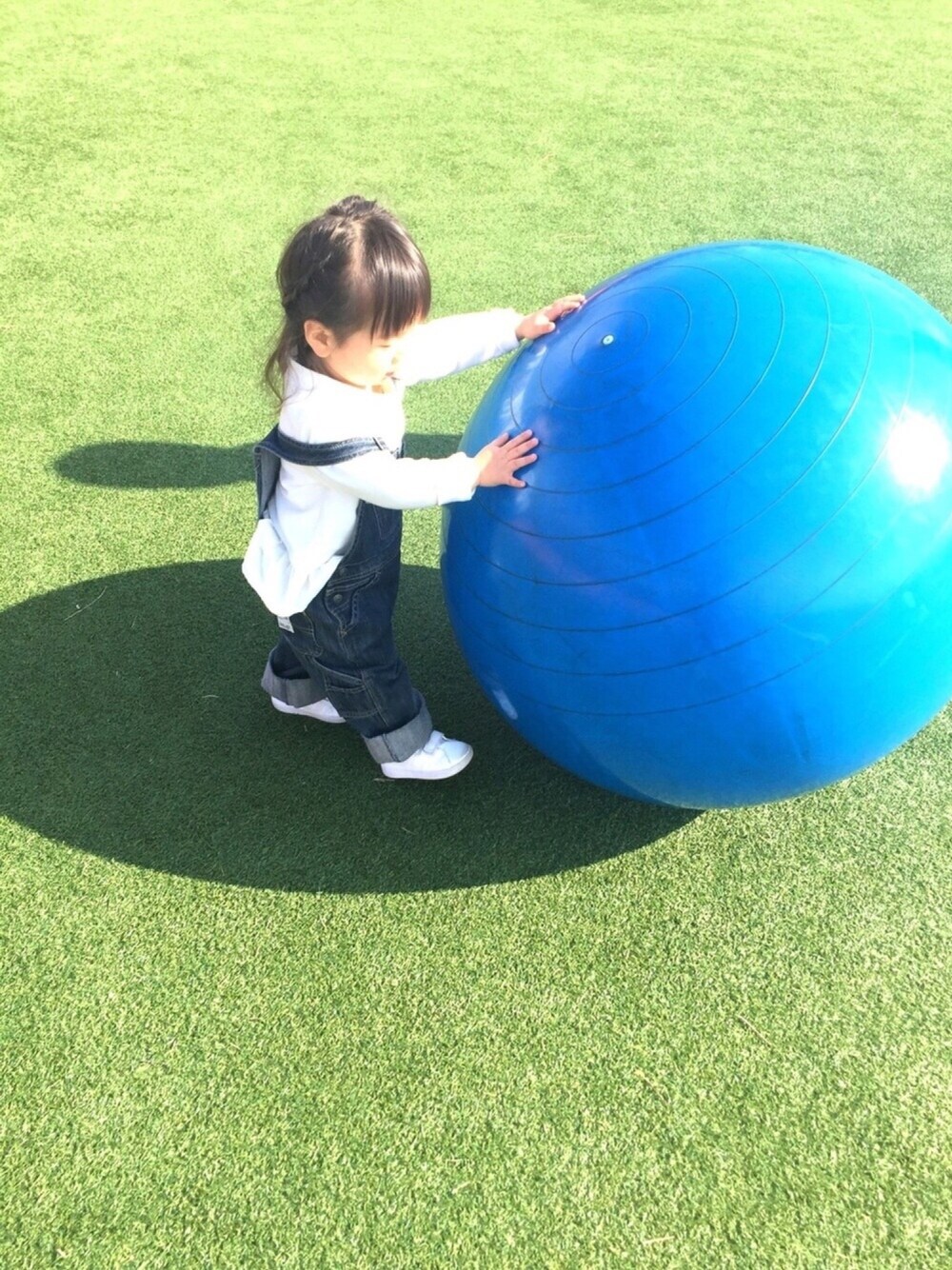 グレー系のニット/セーター、ブルー系のサロペット/オーバーオール、ホワイト系のスニーカーを着用したキッズの冬コーディネートの1枚目の写真