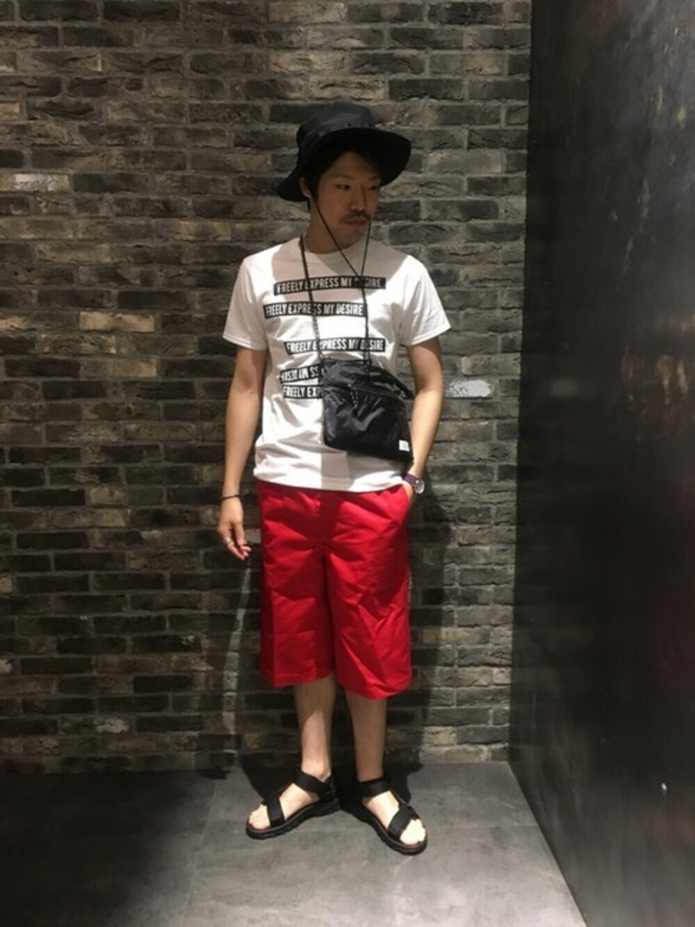 ホワイト系のトップス、ブラック系のシューズ、パープル系のバッグを着用したメンズの夏コーディネートの1枚目の写真