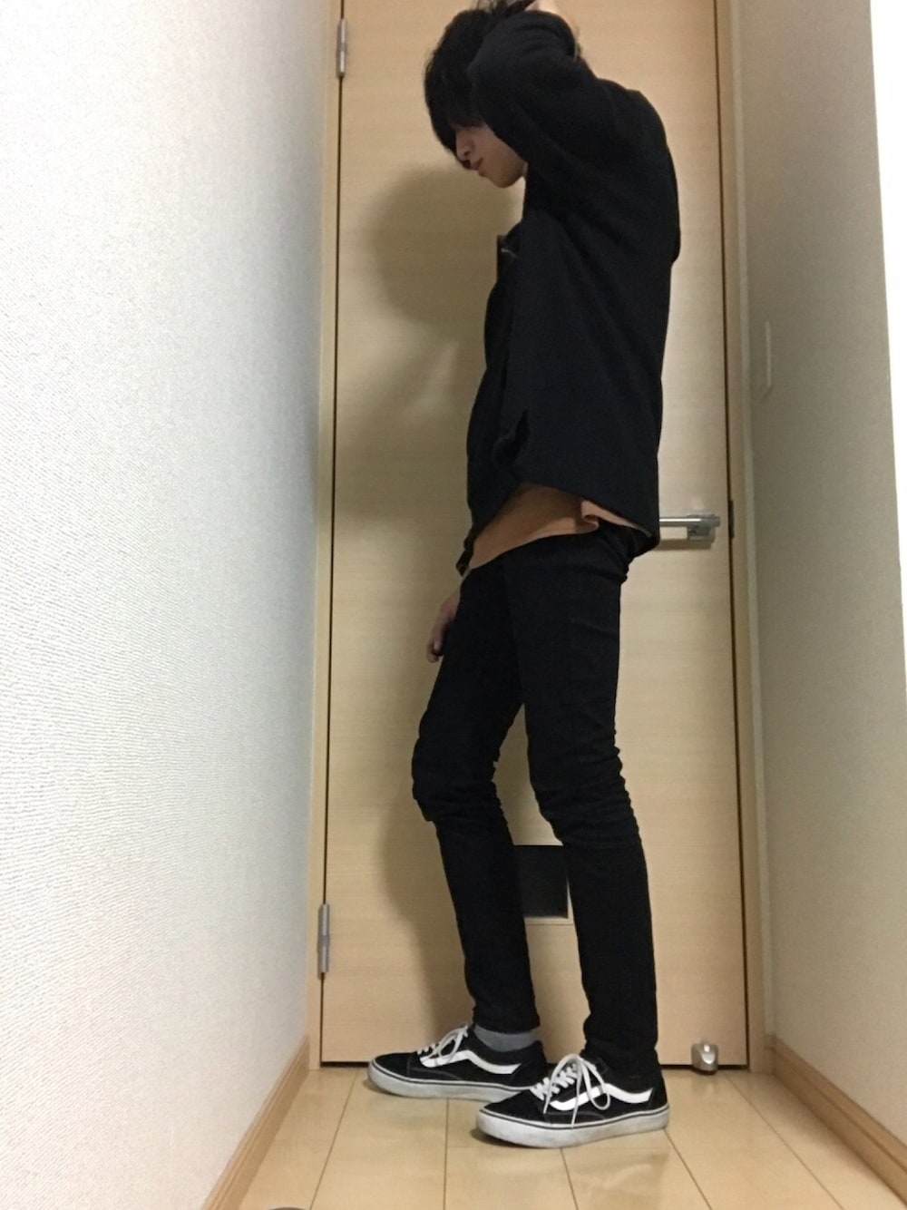 ブラック系のデニムパンツ、ブラック系のパーカー、イエロー系のTシャツ/カットソーを着用したメンズの春コーディネートの1枚目の写真