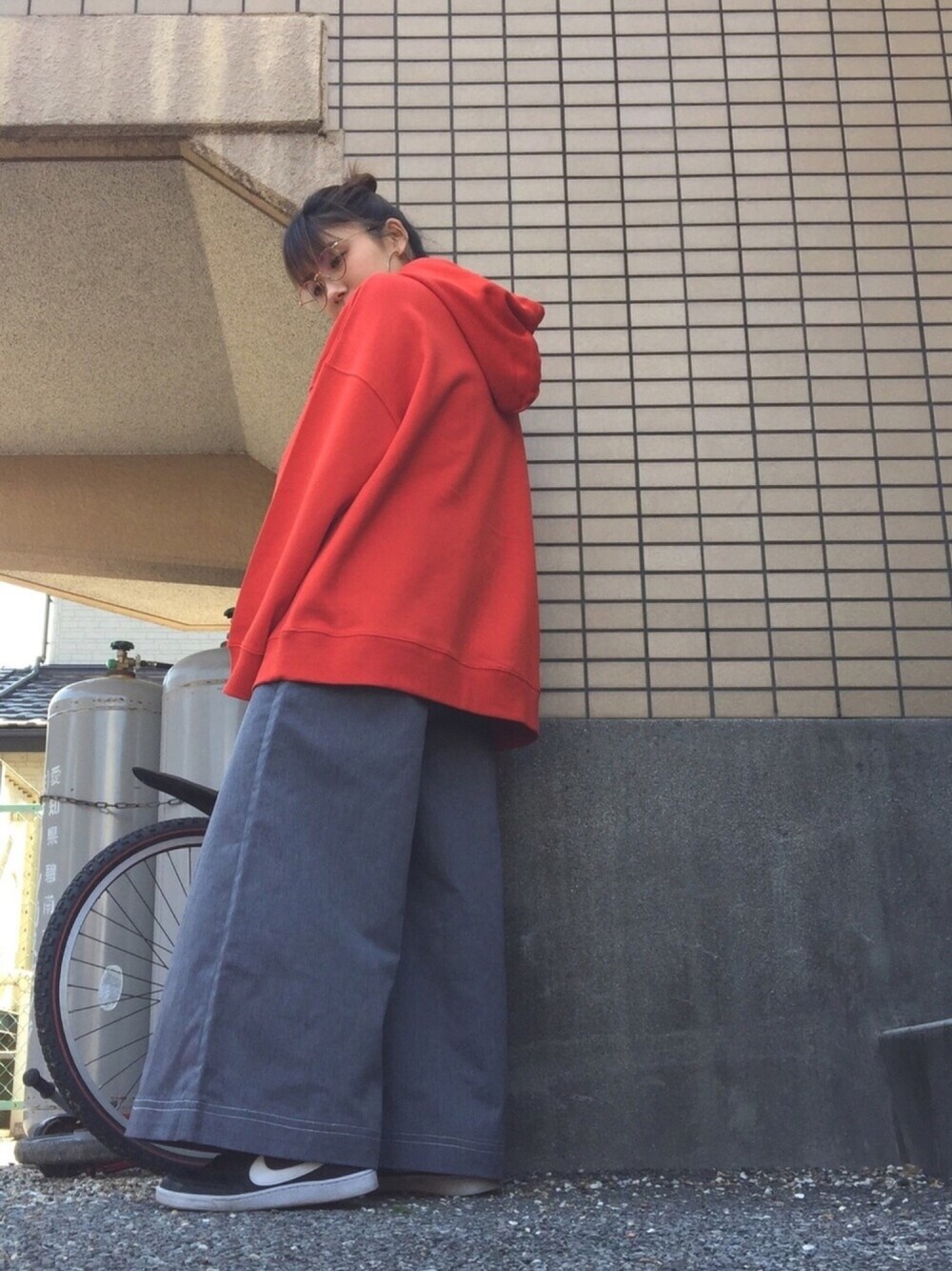 グレー系のチノパンツ、ブラック系のスニーカー、オレンジ系のパーカーを着用したレディースの春コーディネートの1枚目の写真