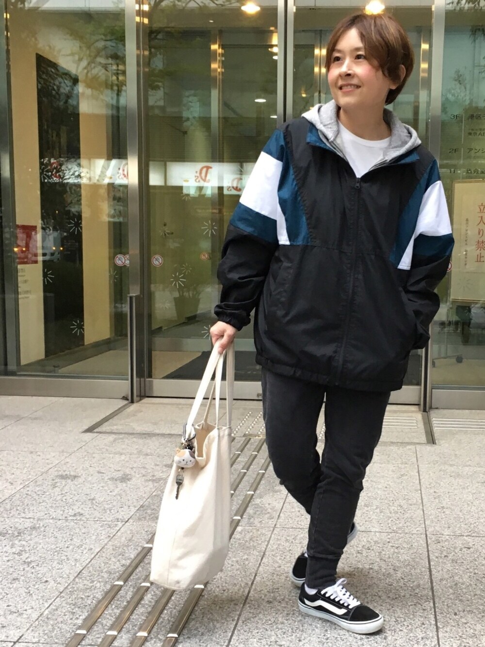 ブラック系のナイロンジャケット、グレー系のパーカー、ブラック系のその他パンツを着用したレディースの春コーディネートの1枚目の写真