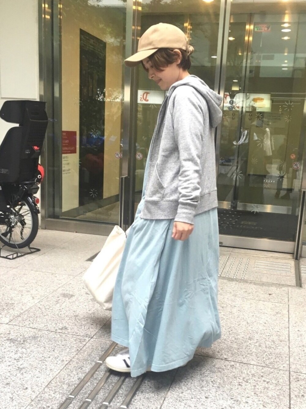 グレー系のパーカー、ブルー系のワンピース/ドレス、ホワイト系のスニーカーを着用したレディースの春コーディネートの1枚目の写真