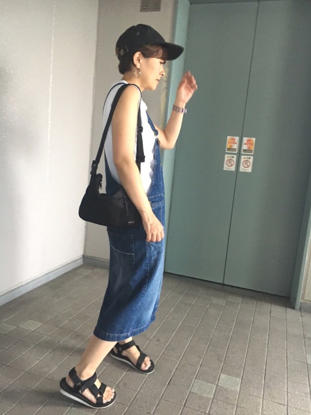 ホワイト系のタンクトップ、ブルー系のサロペット/オーバーオール、ブラック系のサンダルを着用したレディースの夏コーディネートの1枚目の写真