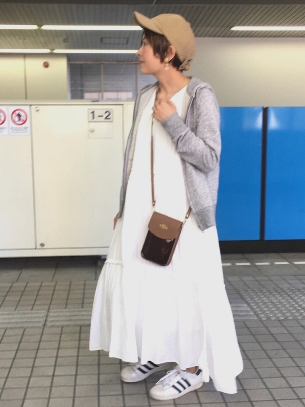 グレー系のパーカー、ブラウン系のショルダーバッグ、ホワイト系のスニーカーを着用したレディースの春コーディネートの1枚目の写真