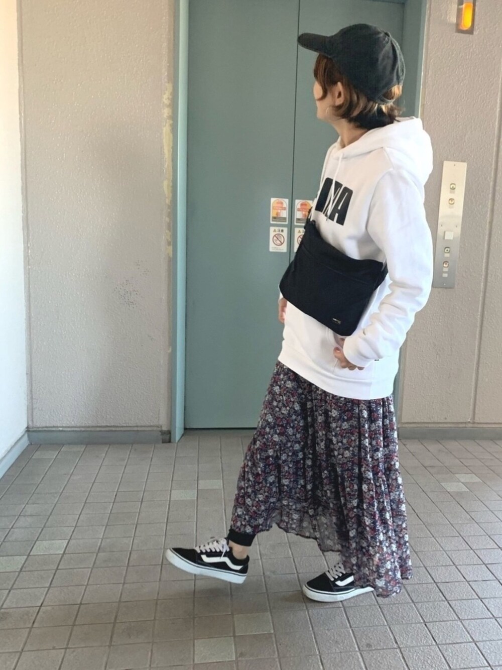 ホワイト系のパーカー、レッド系のスカート、ブラック系のスニーカーを着用したレディースの秋コーディネートの1枚目の写真