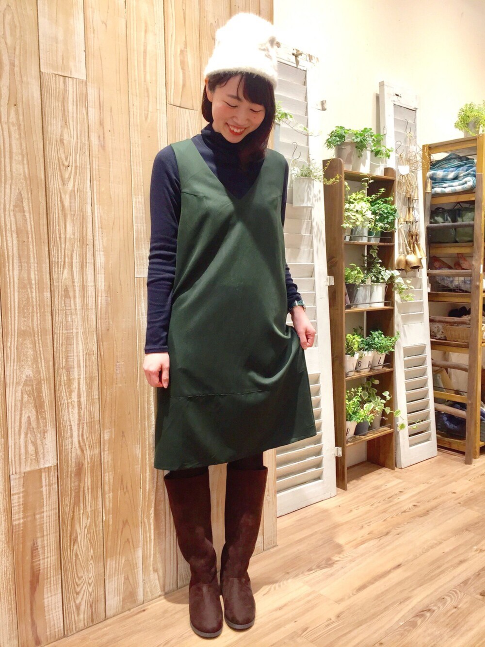 グリーン系のワンピース/ドレス、ブラウン系のブーツ、ホワイト系の帽子を着用したレディースの冬コーディネートの1枚目の写真