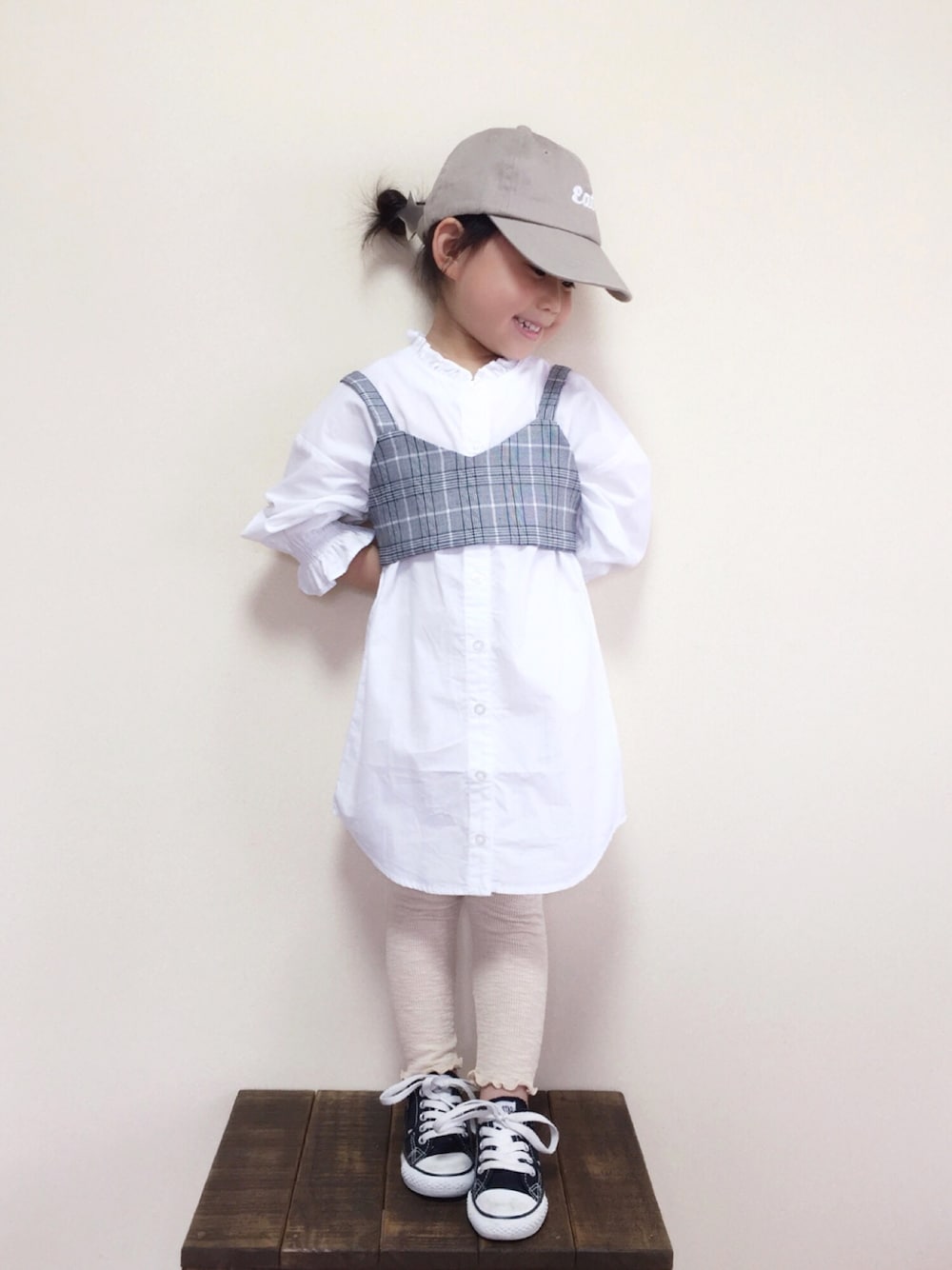 「キッズコーデ、キャップ、シャツワンピ、ビスチェ、レギンス、韓国子供服、コンバース、おしゃれさんと繋がりたい」｜「petit mainのビスチェ付き長袖シャツワンピース（シャツワンピース、ホワイト系）」を使った、bow-changさん（キッズ・100cm）の夏コーディネートの1枚目の写真