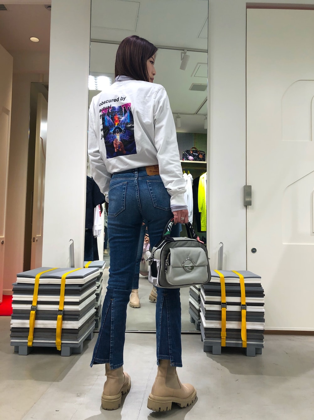 ブルー系のデニムパンツ、シルバー系のハンドバッグ、ホワイト系のTシャツ/カットソーを着用したレディースの春コーディネートの1枚目の写真