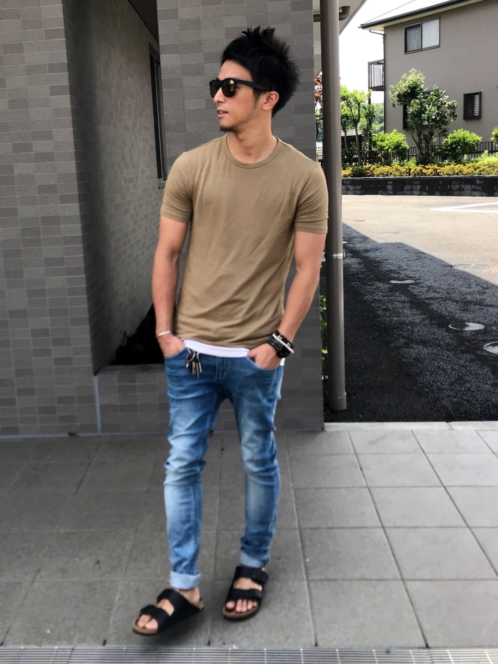 ベージュ系のTシャツ/カットソー、ブルー系のデニムパンツ、ブラック系のサンダルを着用したメンズの夏コーディネートの1枚目の写真