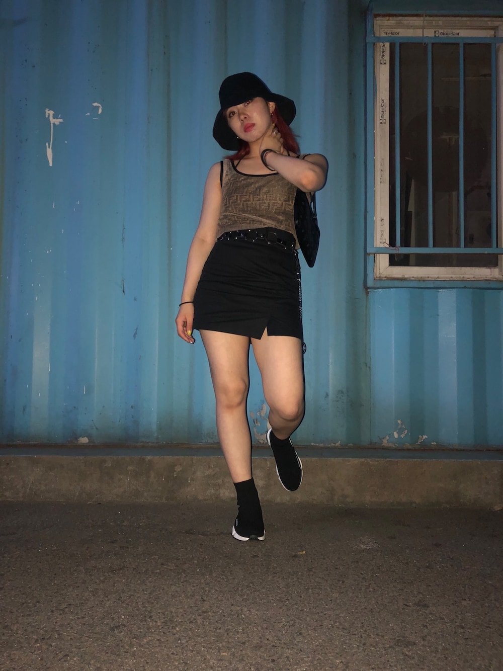 ブラック系のスカート、ブラック系のスニーカー、ブラック系のクラッチバッグを着用したレディースの夏コーディネートの1枚目の写真