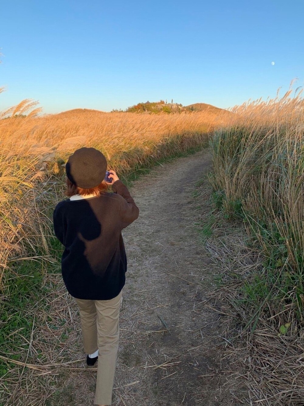 ブラック系のノーカラージャケット、ベージュ系のチノパンツを着用したレディースの冬コーディネートの1枚目の写真