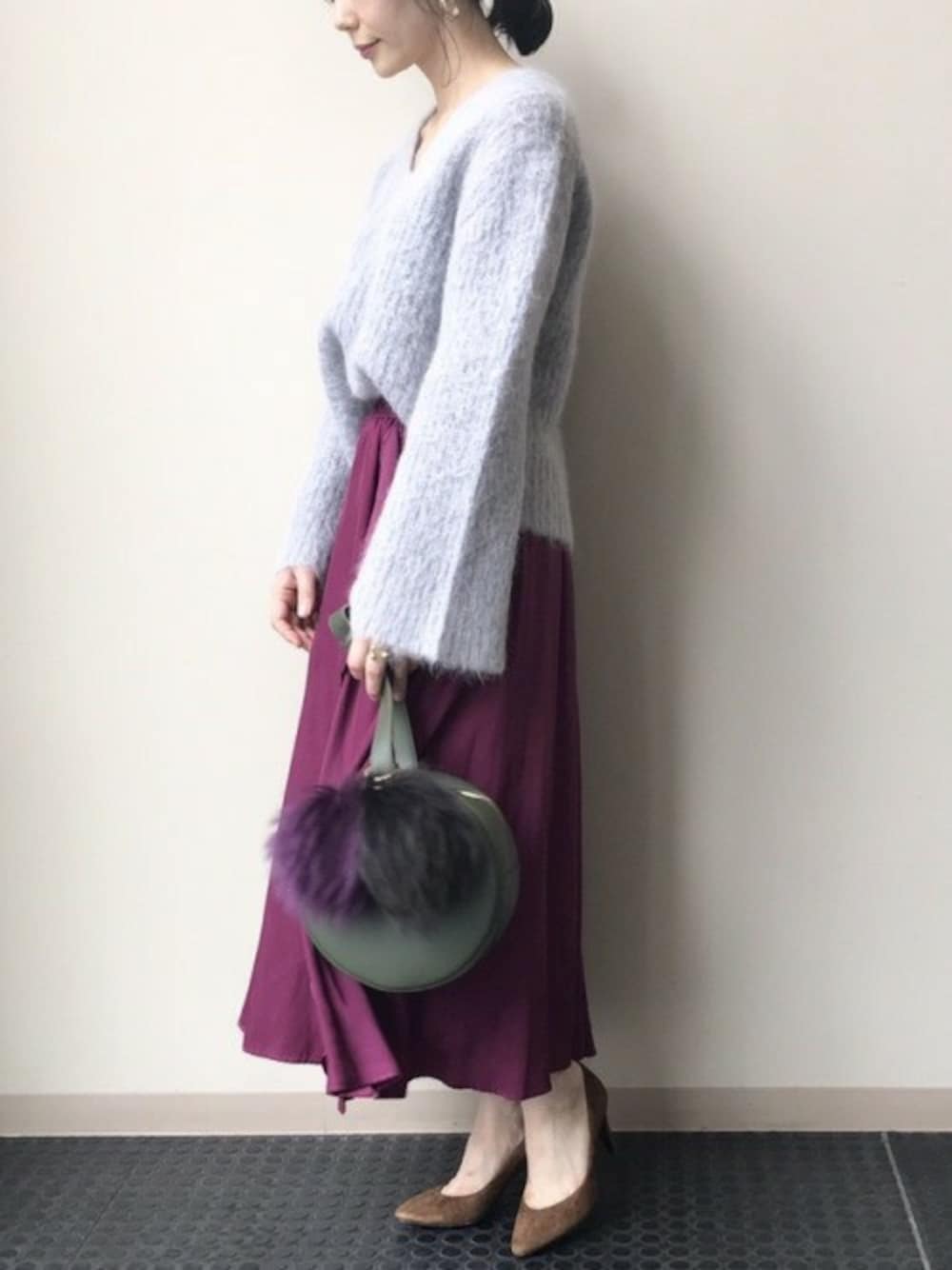 グレー系のニット/セーター、ピンク系のスカート、グリーン系のショルダーバッグを着用したレディースの秋コーディネートの1枚目の写真