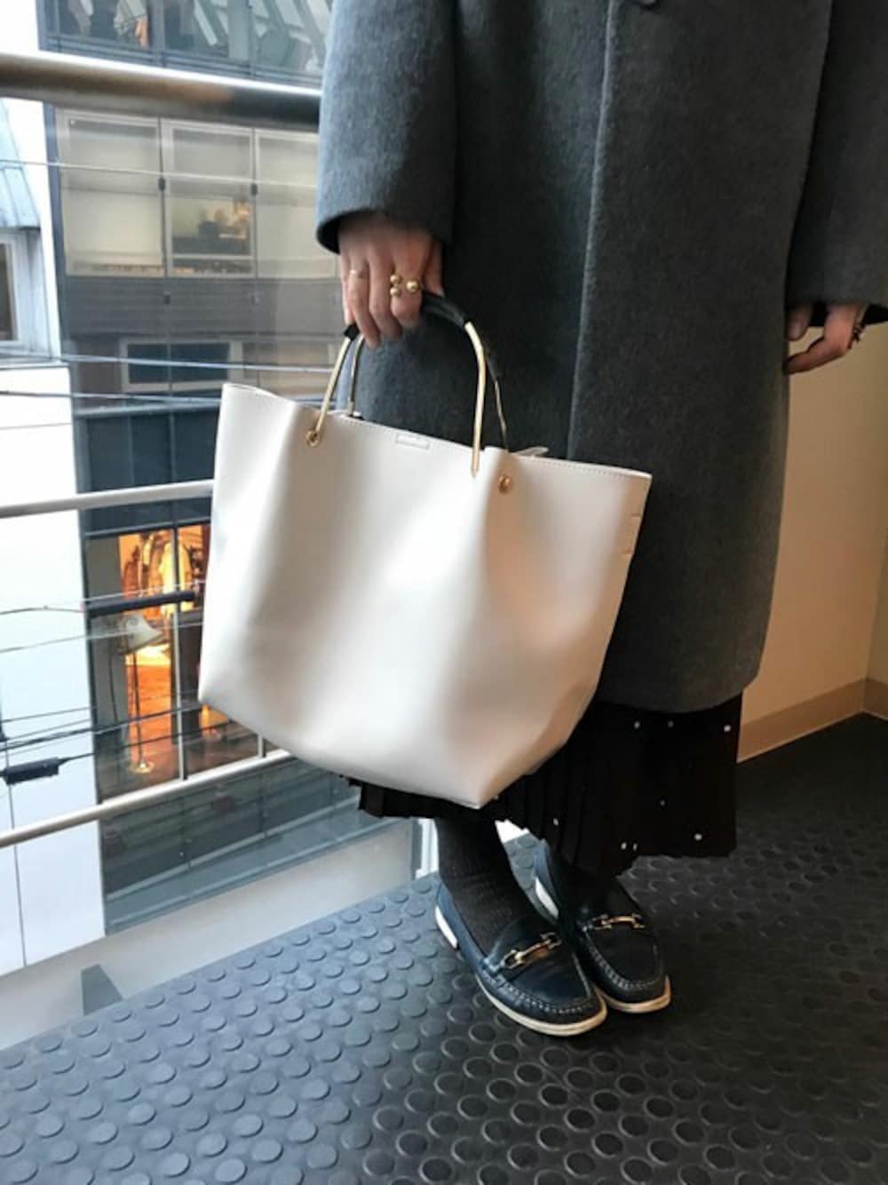 グレー系のチェスターコート、ベージュ系のトートバッグ、ゴールド系のリングを着用したレディースの冬コーディネートの1枚目の写真