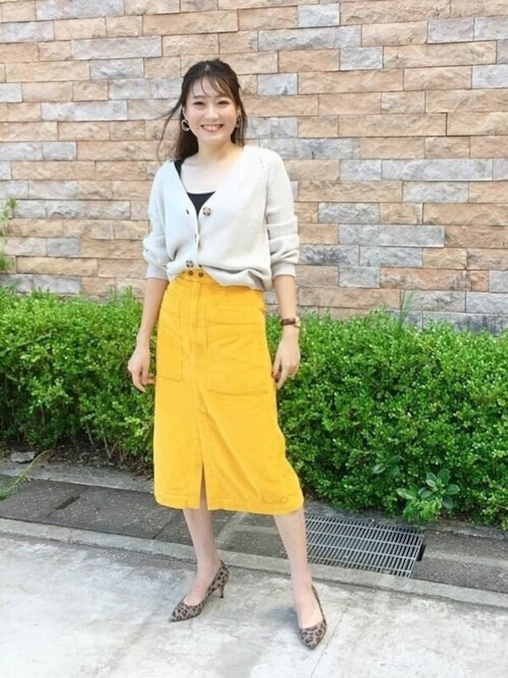 イエロー系のスカート、ブラック系のタンクトップ、ベージュ系のカーディガン/ボレロを着用したレディースの秋コーディネートの1枚目の写真