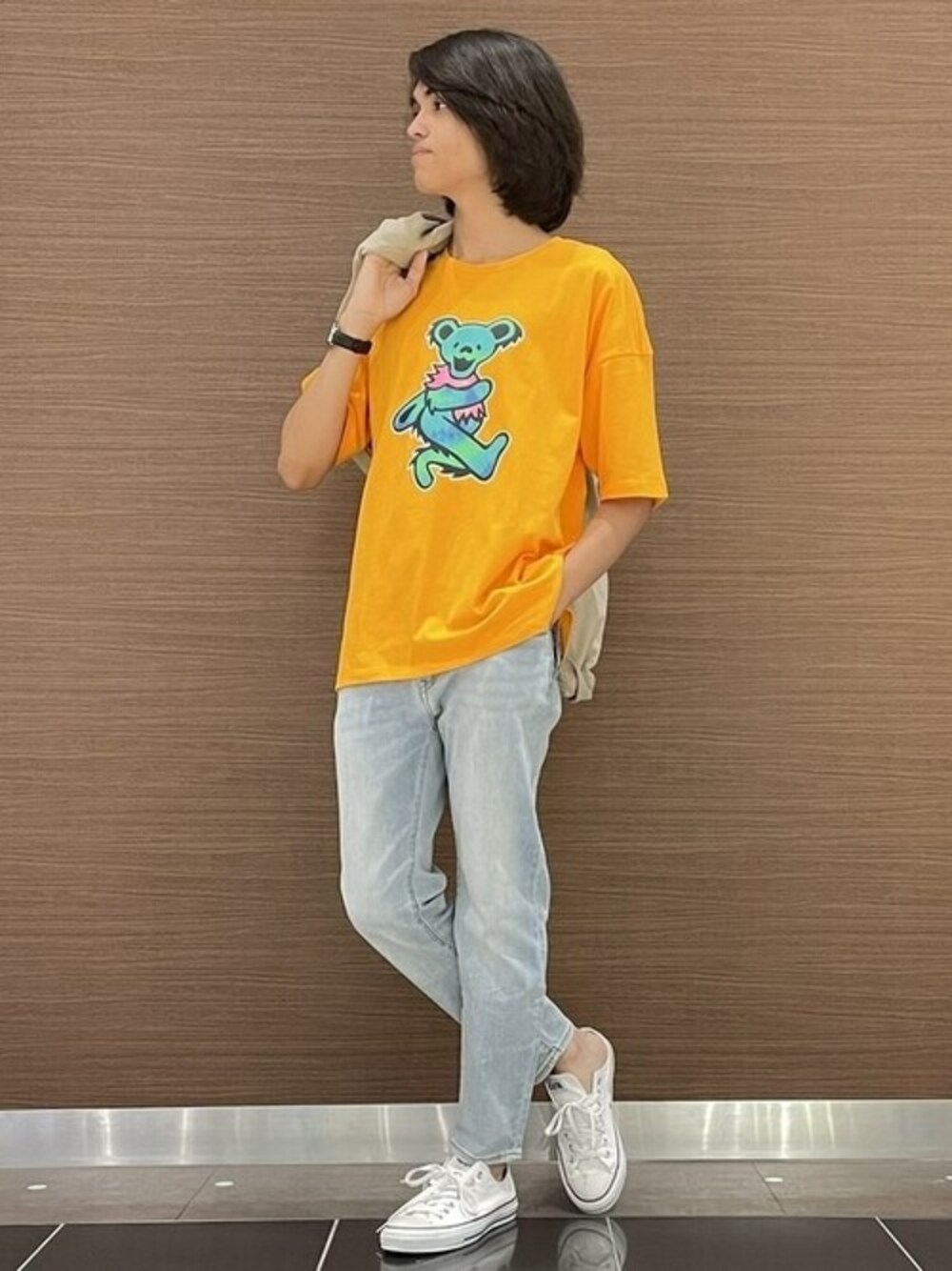 オレンジ系のTシャツ/カットソー、ブルー系のデニムパンツ、ブラウン系のスウェットを着用したメンズの夏コーディネートの1枚目の写真