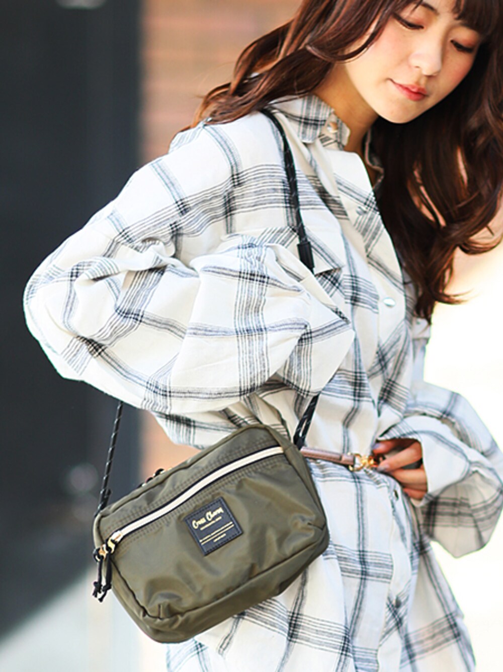 グリーン系のショルダーバッグを着用したレディースの冬コーディネートの1枚目の写真