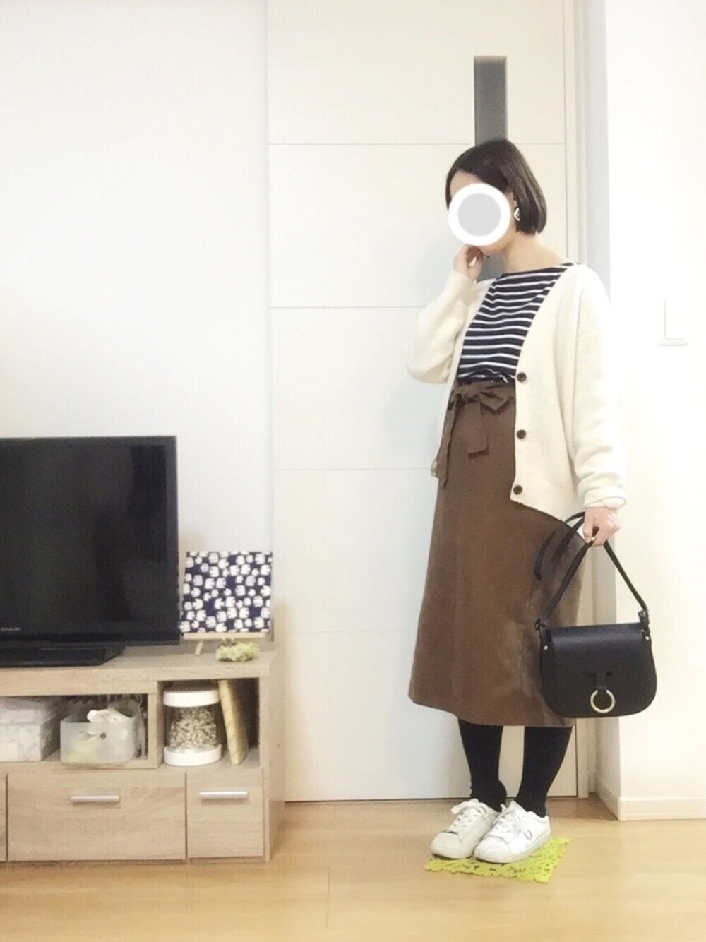 ホワイト系のカーディガン/ボレロ、ホワイト系のスニーカー、ブラック系のバッグを着用したレディースの冬コーディネートの1枚目の写真