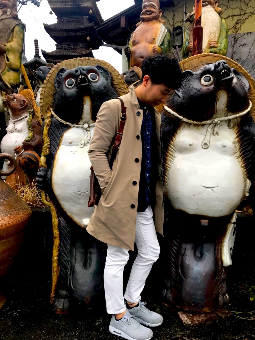 ベージュ系のステンカラーコート、ブルー系のシャツ/ブラウス、ブラック系のカーディガン/ボレロを着用したメンズの春コーディネートの1枚目の写真