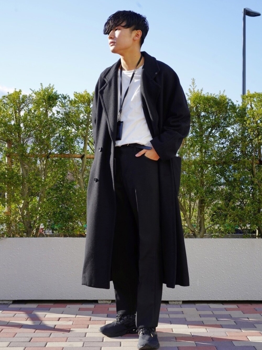 ブラック系のチェスターコート、ホワイト系のTシャツ/カットソー、ブラック系のパンツを着用したメンズの冬コーディネートの1枚目の写真