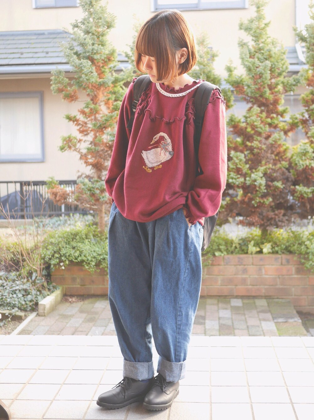 レッド系のスウェット、ブラック系のバックパック/リュック、ブルー系のその他パンツを着用したレディースの冬コーディネートの1枚目の写真