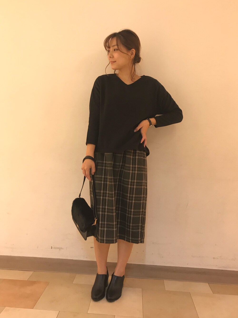 ブラック系のトップス、グリーン系のスカート、ブラック系のショルダーバッグを着用したレディースの秋コーディネートの1枚目の写真