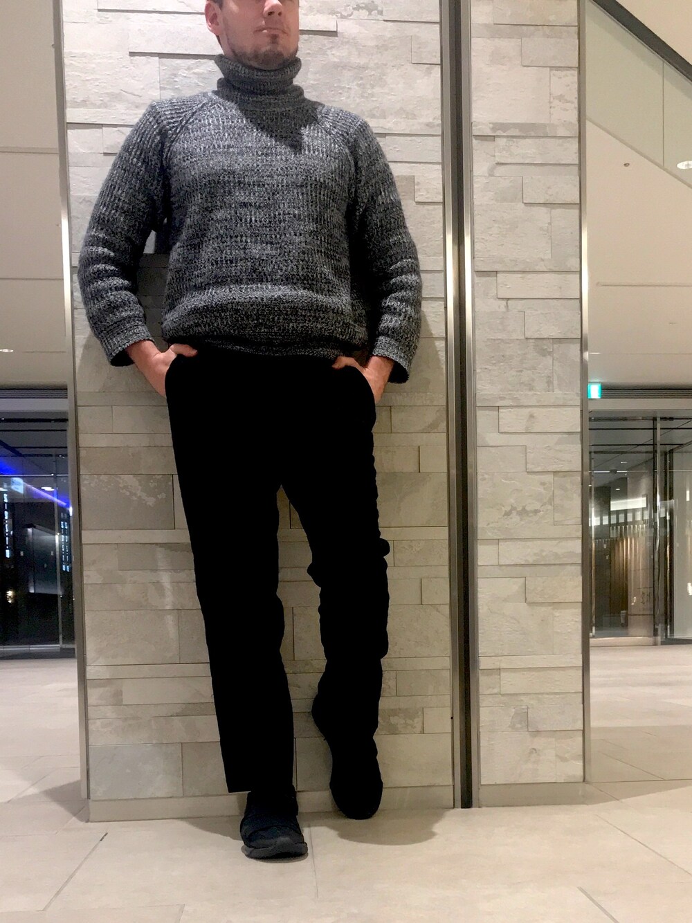 グレー系のニット/セーター、ブラック系のスニーカーを着用したメンズの冬コーディネートの1枚目の写真