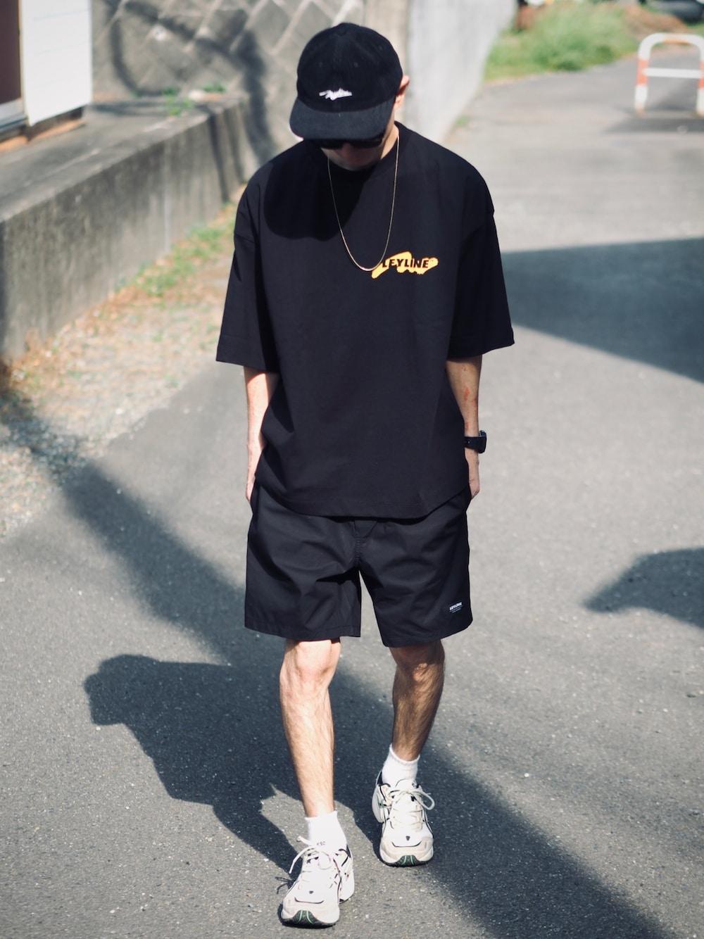 ブラック系のTシャツ/カットソー、ブラック系のその他パンツ、ベージュ系のスニーカーを着用したメンズの春コーディネートの1枚目の写真