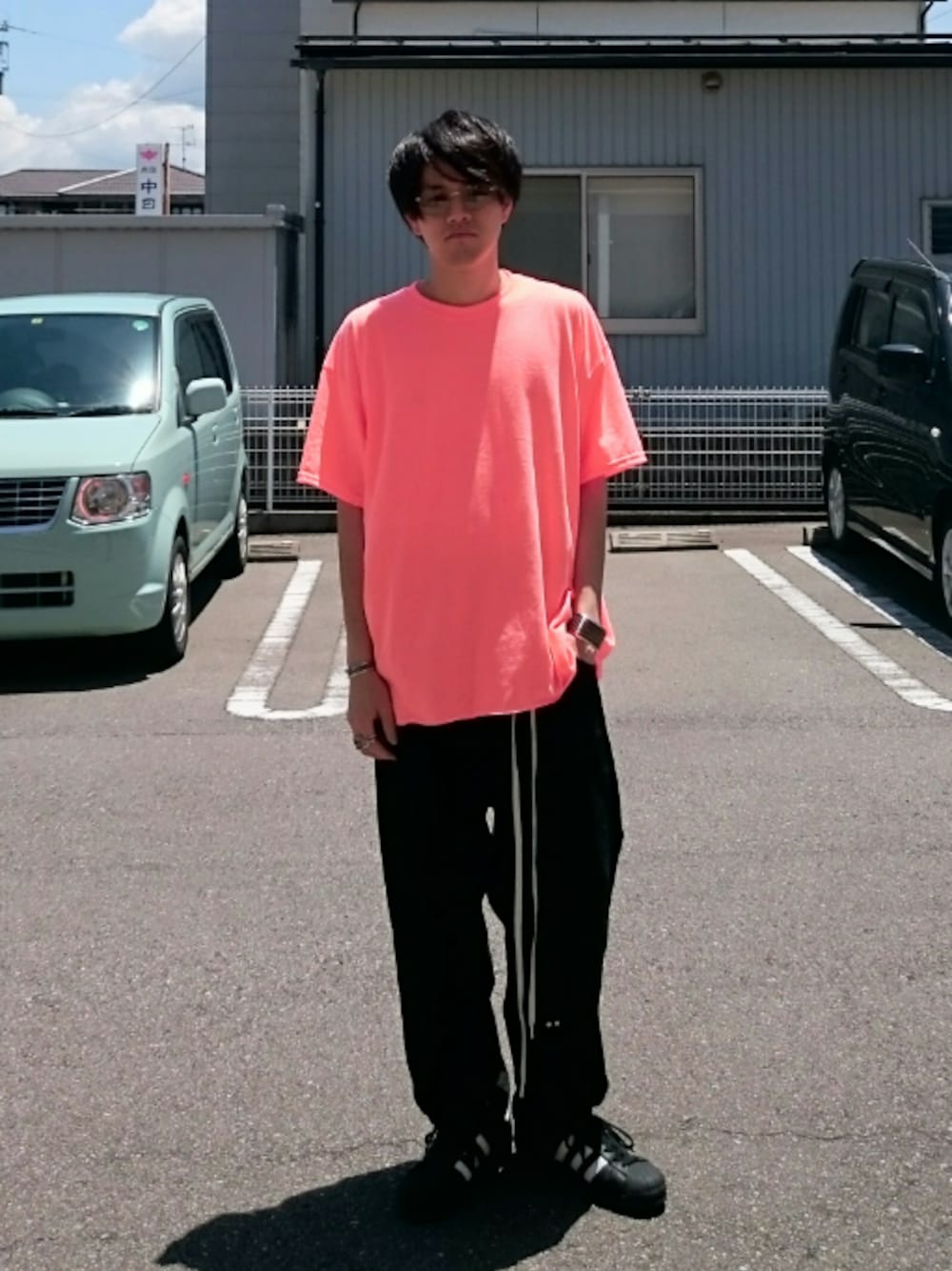 オレンジ系のTシャツ/カットソー、ブラック系のスニーカー、ブラック系のデニムパンツを着用したメンズの夏コーディネートの1枚目の写真