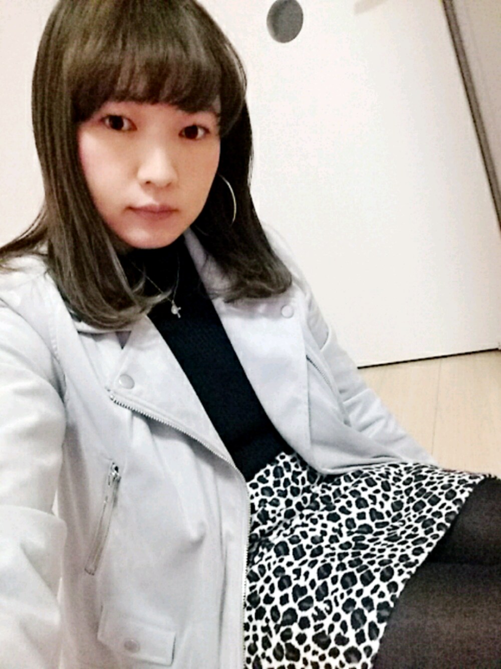 ブラック系のスカート、グレー系のライダースジャケット、ゴールド系のピアス(両耳用)を着用したレディースの春コーディネートの1枚目の写真