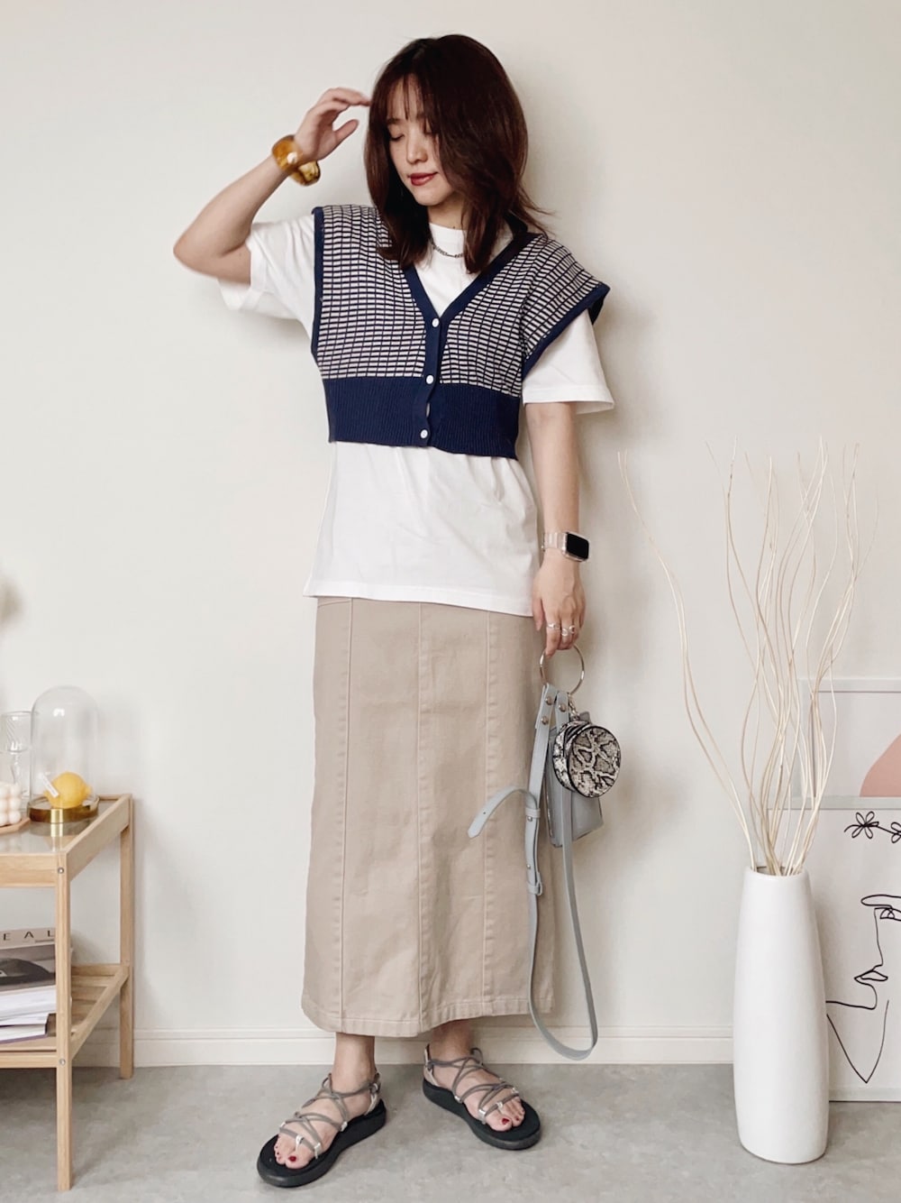 ブルー系のベスト、ホワイト系のTシャツ/カットソー、ベージュ系のデニムスカートを着用したレディースの夏コーディネートの1枚目の写真