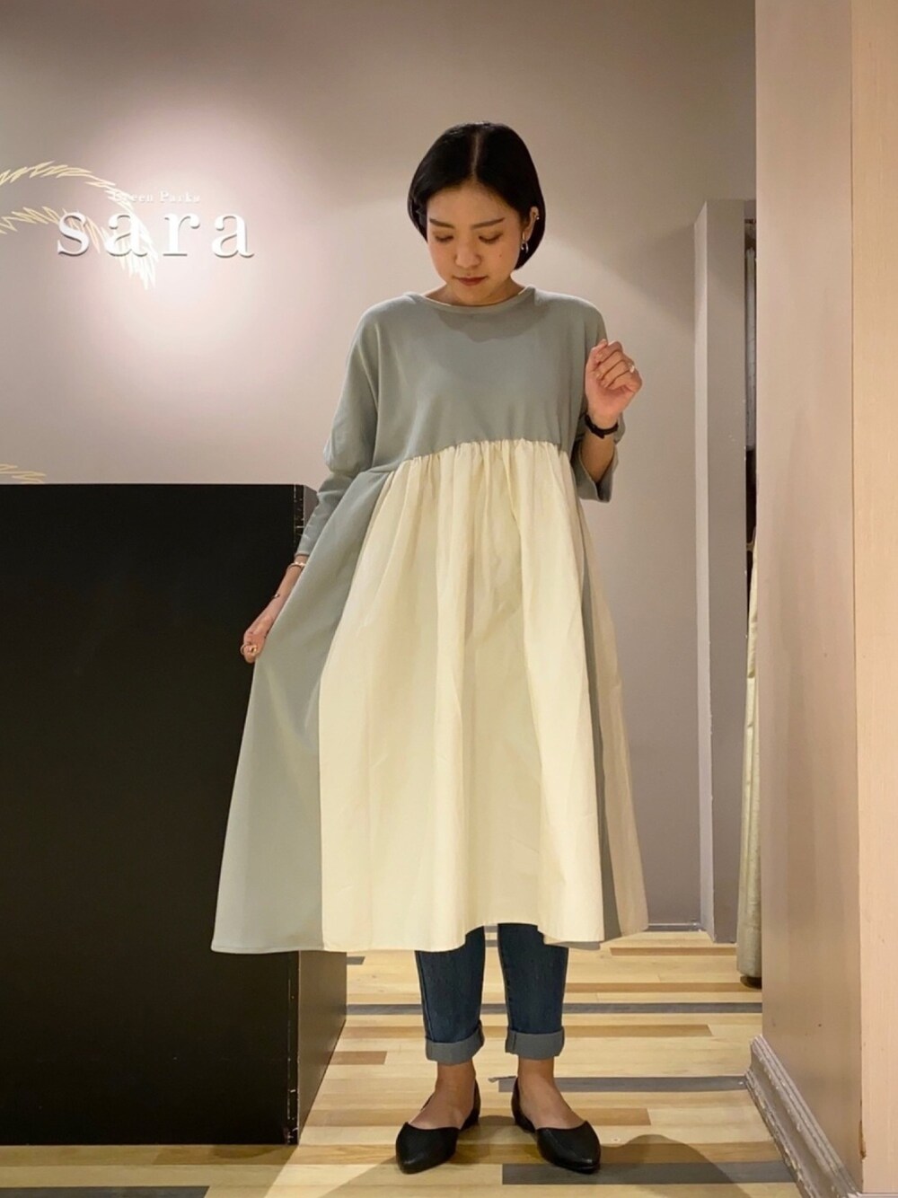 ブルー系のデニムパンツ、ブラック系のパンプス、グリーン系のチュニックを着用したレディースの春コーディネートの1枚目の写真
