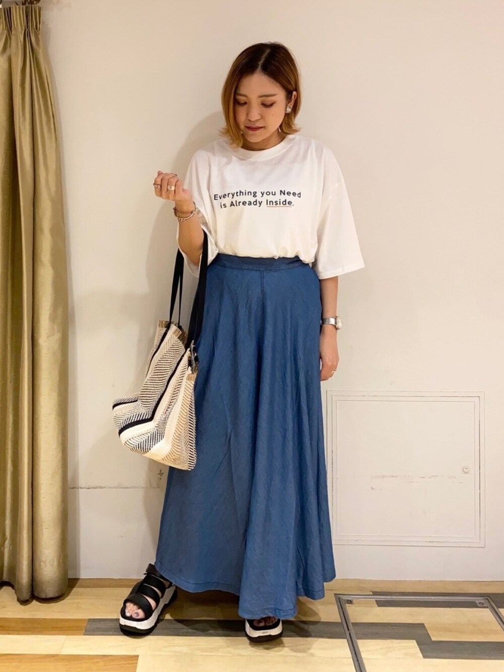 ホワイト系のTシャツ/カットソー、ブルー系のデニムスカート、ブラック系のトートバッグを着用したレディースの夏コーディネートの1枚目の写真