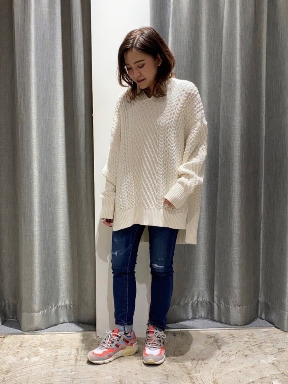 グレー系のスニーカー、ブルー系のデニムパンツ、ホワイト系のニット/セーターを着用したレディースの冬コーディネートの1枚目の写真