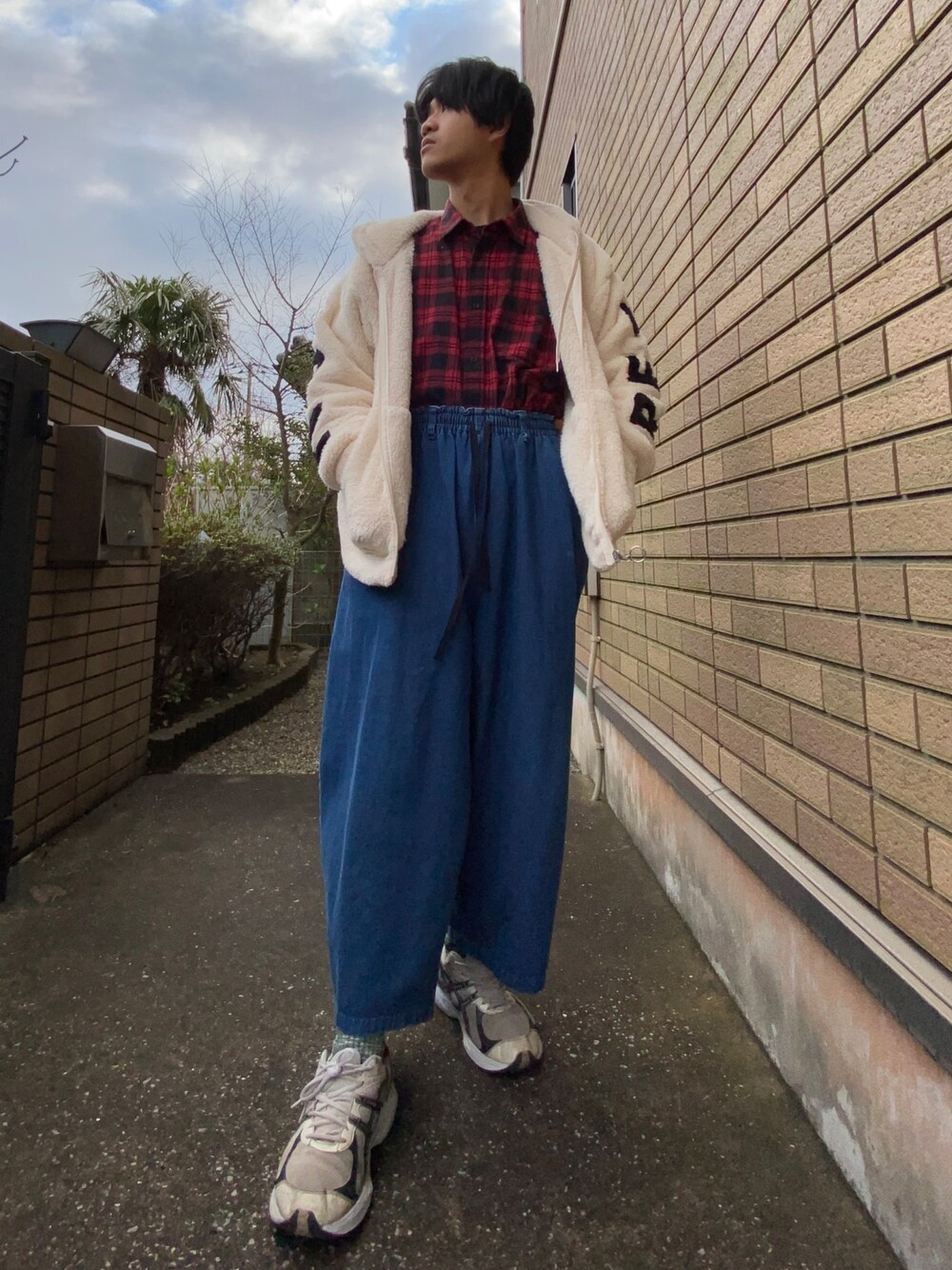 ブルー系のデニムパンツ、レッド系のシャツ/ブラウス、ベージュ系のパーカーを着用したメンズの春コーディネートの1枚目の写真