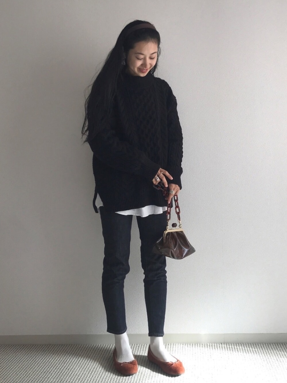 ブラック系のニット/セーター、ホワイト系のTシャツ/カットソー、ブルー系のデニムパンツを着用したレディースの冬コーディネートの1枚目の写真